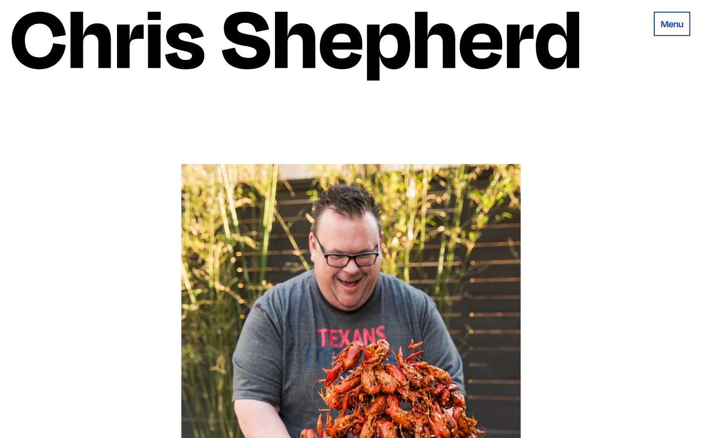 The Chris Shepherd website: an oversized black Chris Shepherd wordmark across the top of a white page, a blue Menu button, and a photograph of Chris Shepherd laughing while holding a tray of crawfish